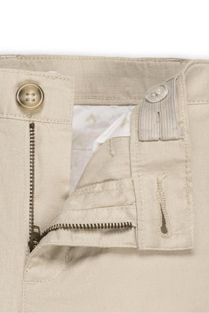 Close-up of beige linen pants showing a zip fly, faux tortoiseshell button, and adjustable waistband for a comfortable fit.