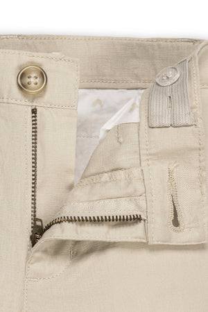 Close-up of beige linen and organic cotton blend suit pants featuring a zip fly and faux tortoiseshell button closure. The adjustable inner waistband ensures comfort for baby boys.