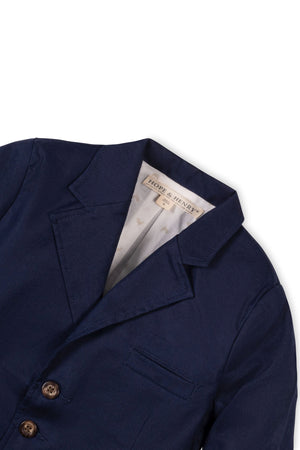 Navy linen suit jacket with a notch collar, faux tortoiseshell buttons, and a welt pocket, designed for boys.