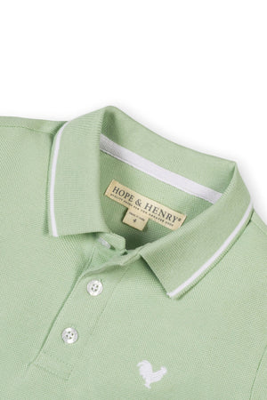 A soft green organic cotton polo shirt by Hope & Henry features a textured knit pique, flat-knit collar, and front button placket, ideal for boys aged 2T-18.