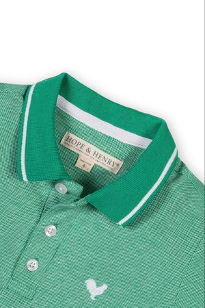 Close-up of a Kelly green Hope & Henry organic cotton polo shirt featuring a textured knit, flat-knit collar, and button.