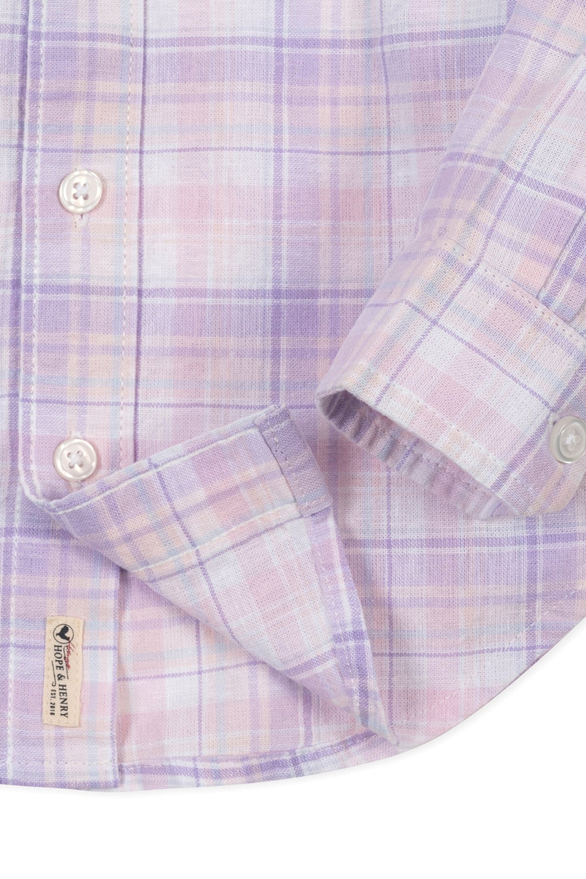 Close-up of a light plaid button-down shirt in lavender and pastel colors, featuring a chest pocket and branded label.