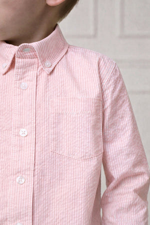 Close-up of a boys long-sleeve, pink seersucker shirt featuring a button-down collar and a chest pocket.