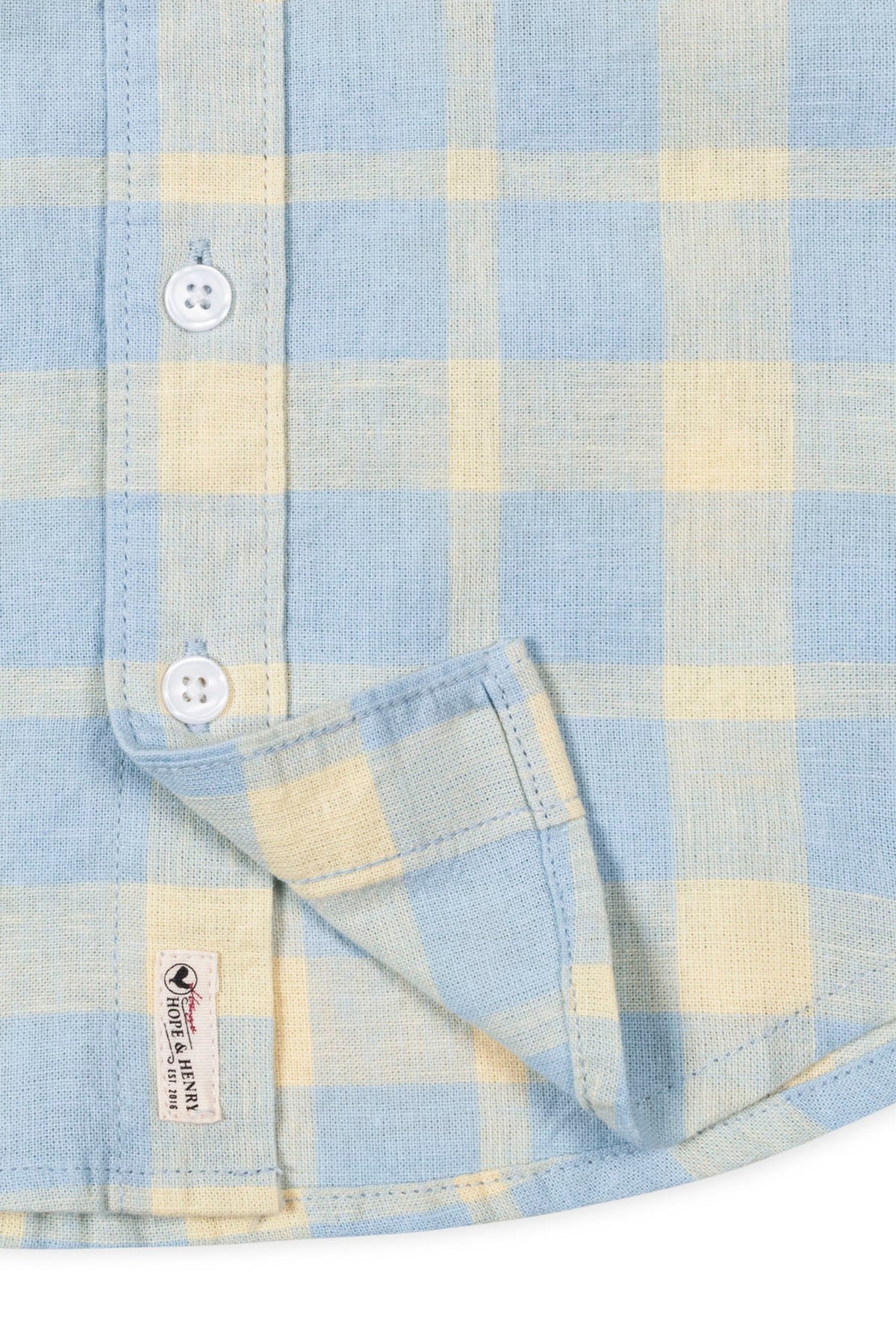Close-up of a Hope & Henry boys linen shirt in sunlit plaid, featuring buttons and a brand tag.