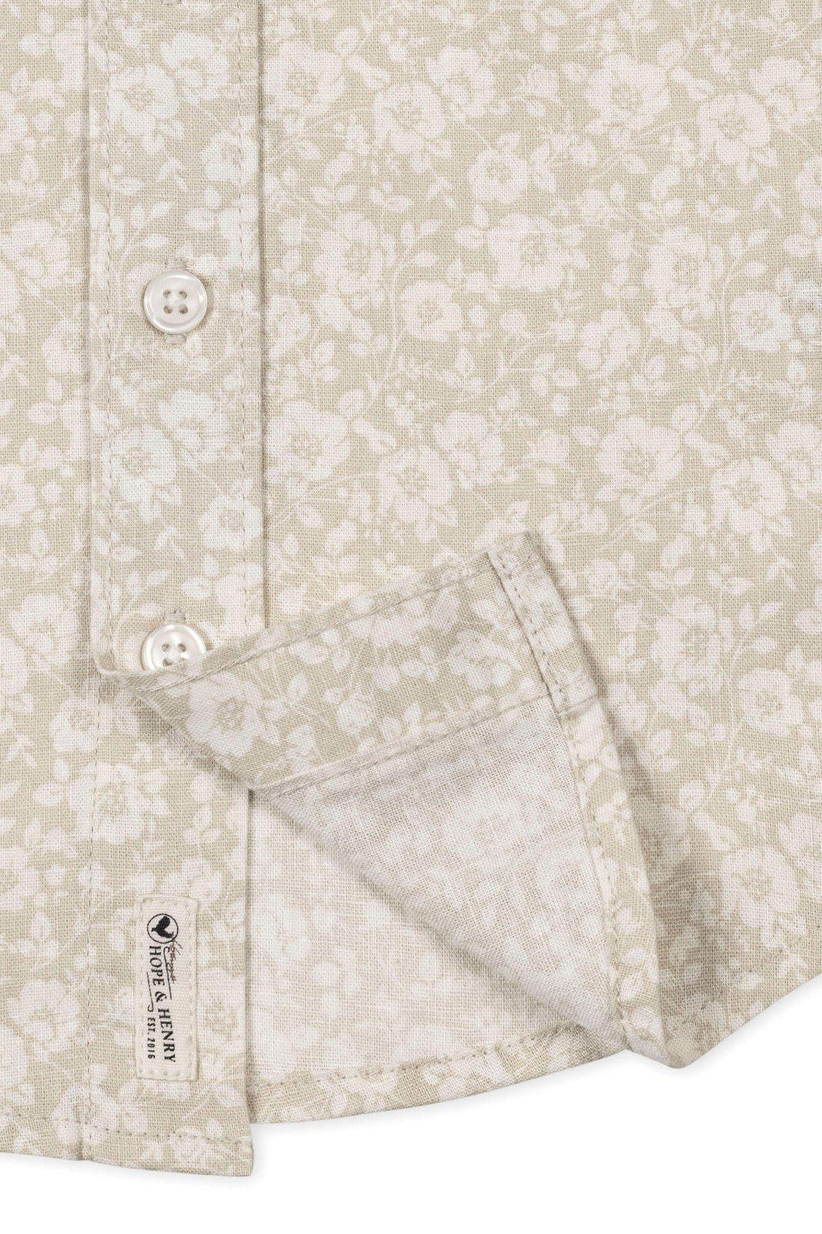 Close-up of a sandy floral short sleeve shirt by Hope & Henry, featuring a button front and breathable linen fabric.