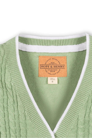 Close-up of a soft green cable knit cardigan with a white ribbed collar and label, designed by Hope & Henry,.