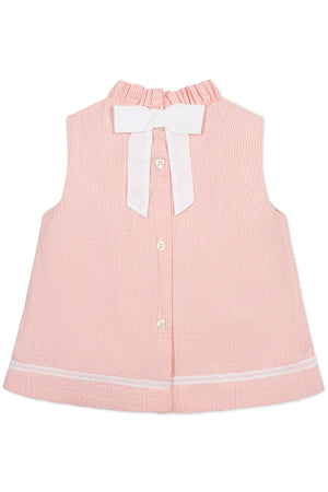 Back view of a pink seersucker top with a ruffle collar, white bow, and button closure, crafted from organic cotton.