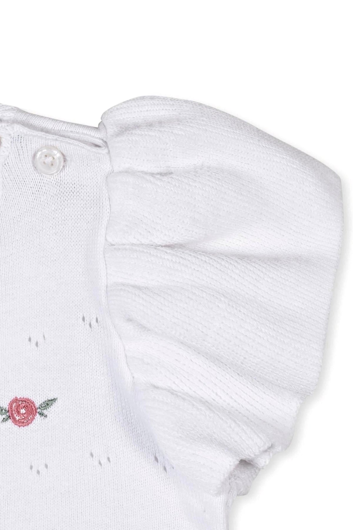Close-up of a white organic cotton sweater featuring ruffle sleeves and a delicate pink rose embroidery detail.