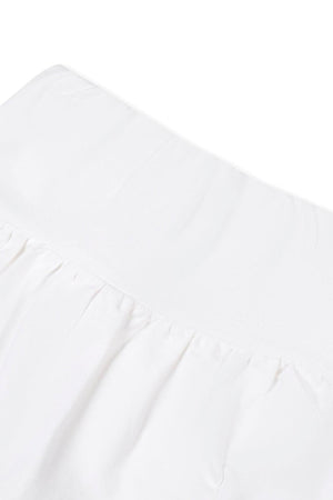 Close-up view of the elastic waistband of a white skort made from soft organic cotton, showcasing its flouncy design and sustainable fabric, ideal for active children.