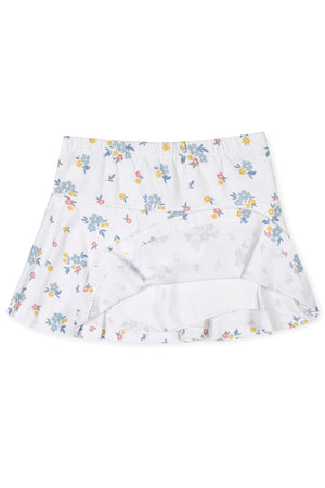 A flouncy skort in soft organic cotton features a white base adorned with colorful floral prints. The design includes an elastic back waist and a jersey inner short for comfort.
