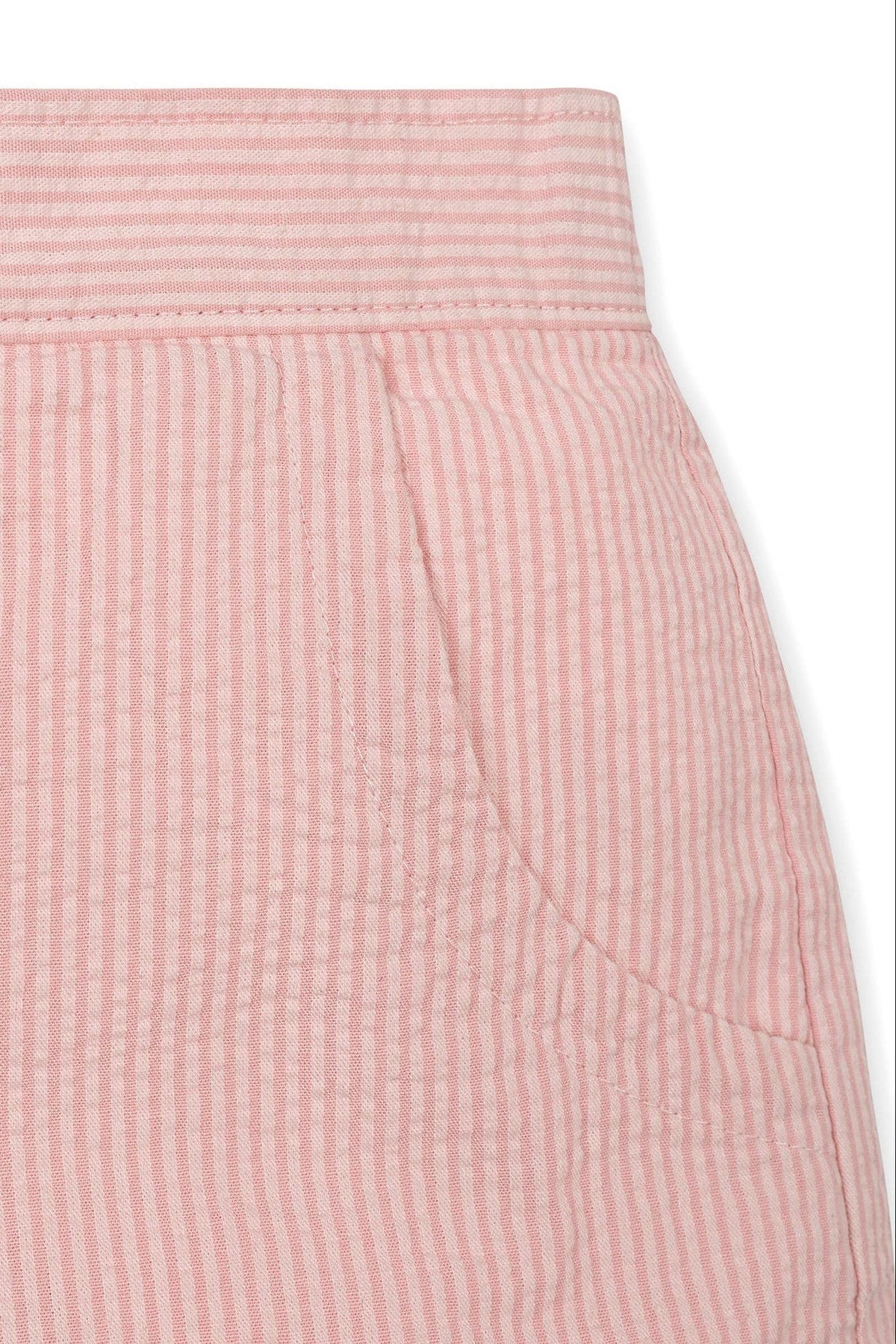 Close-up of pink seersucker fabric showcasing a pocket and textured stripes, ideal for girls organic cotton shorts.