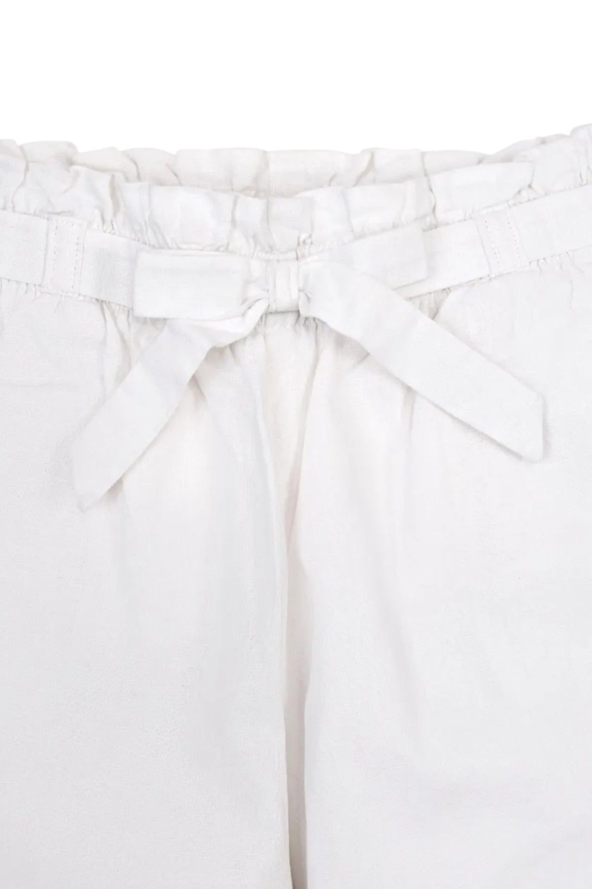 Close-up of a white linen pant waistband featuring an elasticized pull-on design and a decorative bow tie.