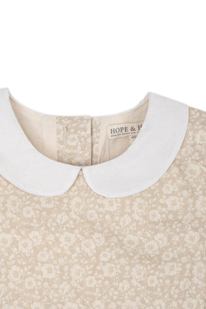 Close-up of a sandy floral dress featuring a white Peter Pan collar and the Hope & Henry label.
