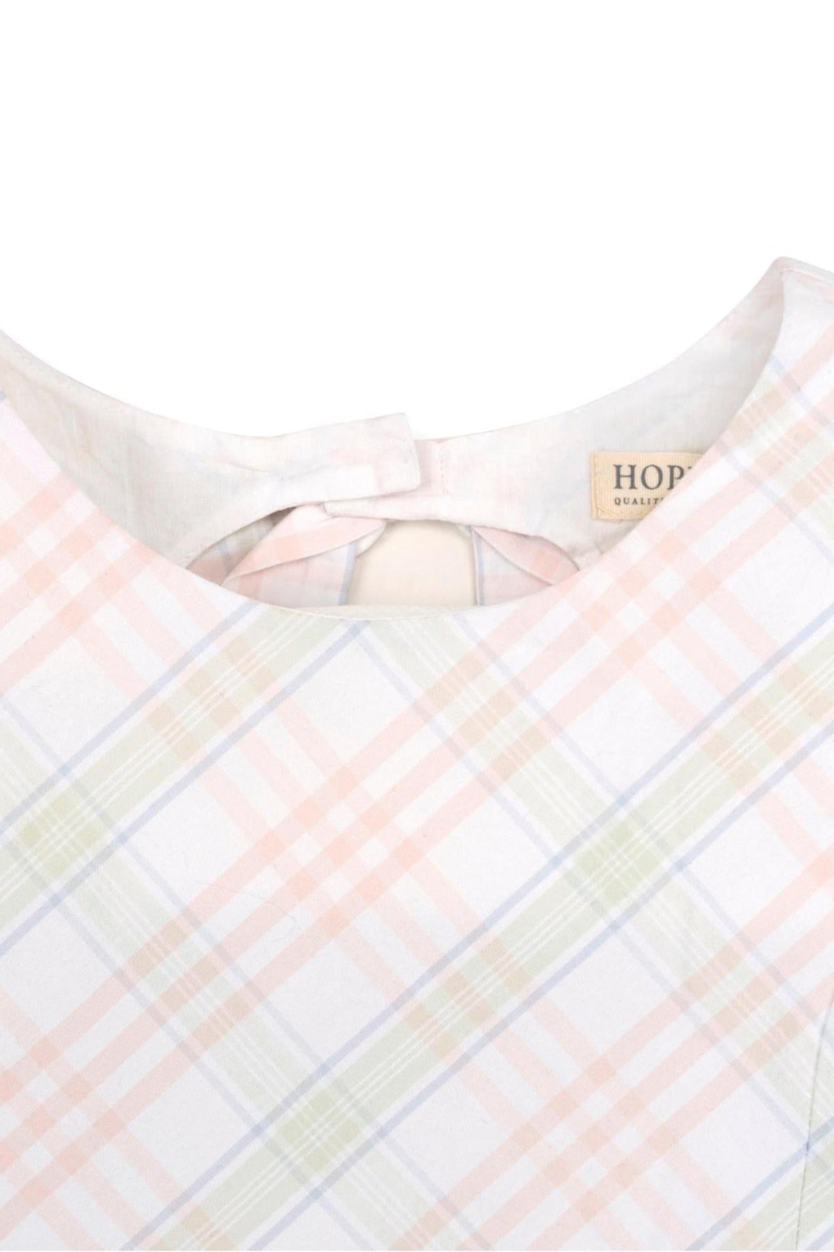 Close-up of a sleeveless dress featuring a pastel plaid pattern, with a bow and button closure at the back.