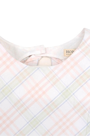 Close-up of a sleeveless dress featuring a pastel plaid pattern, with a bow and button closure at the back.