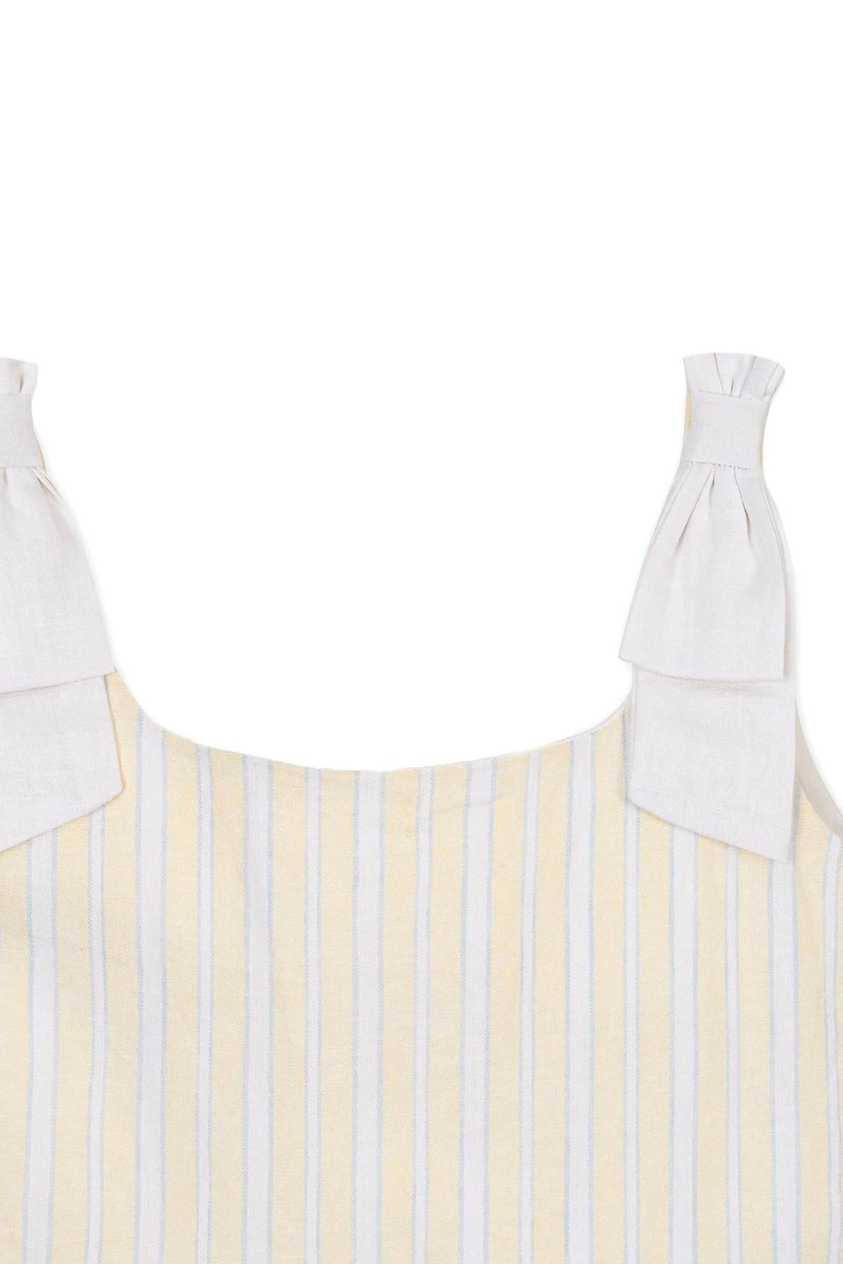 Close-up of a yellow and white striped dress featuring bow shoulder straps made of linen fabric, perfect for warm weather.