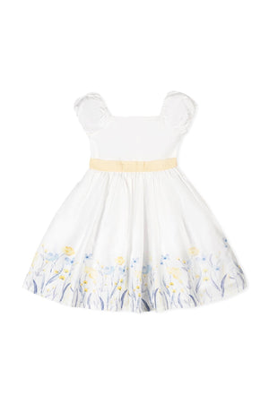 A white organic cotton dress features feminine puff sleeves and a yellow waist sash. The skirt is adorned with delicate floral patterns in blue and yellow, perfect for special occasions.