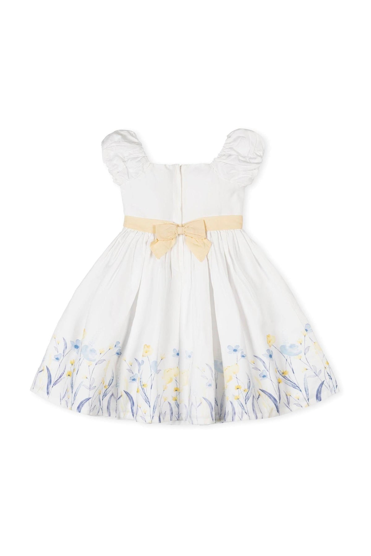 A white organic cotton dress features puff sleeves and a yellow waist sash with a bow. The skirt is adorned with delicate blue and yellow floral patterns.