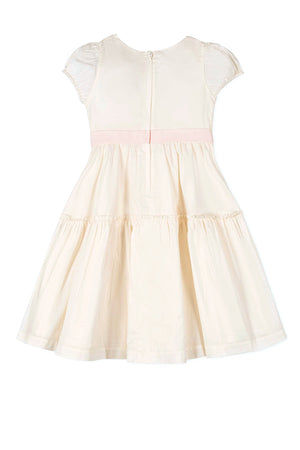Cream-colored girls dress with puff sleeves, pink waist sash, and tiered skirt. Features a back zipper closure.