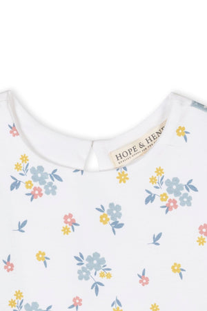 Close-up of a white tank dress featuring a colorful floral print, with a small keyhole opening at the back.