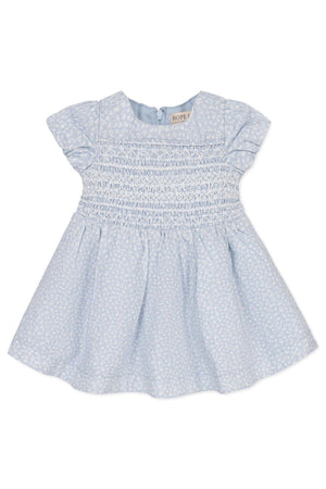 Light blue baby dress with smocked bodice and puff sleeves, featuring a subtle floral pattern. Made from linen blend.