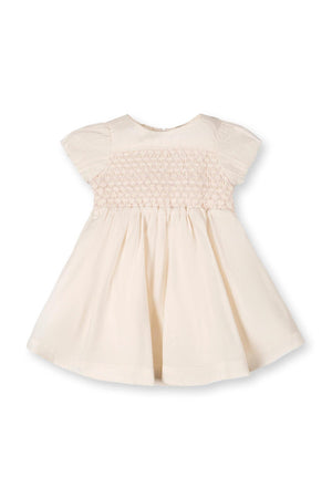Beige organic cotton baby dress featuring a smocked bodice and puff sleeves, designed for infants aged 0-24 months.
