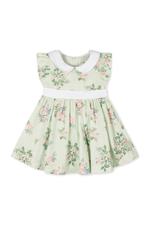 Light green dress with floral patterns, featuring a white Peter Pan collar and flutter sleeves, made from organic cotton.