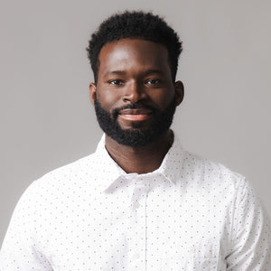 A man smiles while wearing a white short sleeve shirt featuring a subtle dotted pattern. The shirts fabric appears lightweight and breathable, ideal for warm weather.