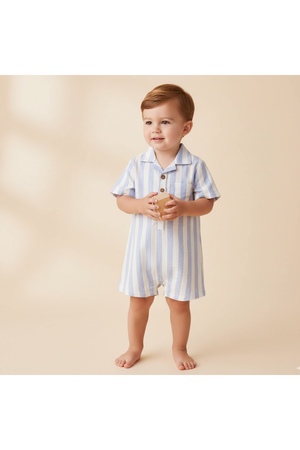 A young child stands barefoot, wearing a blue and white striped organic collared romper. The lightweight fabric features a smart collar and wooden buttons, perfect for warm, sunny days.