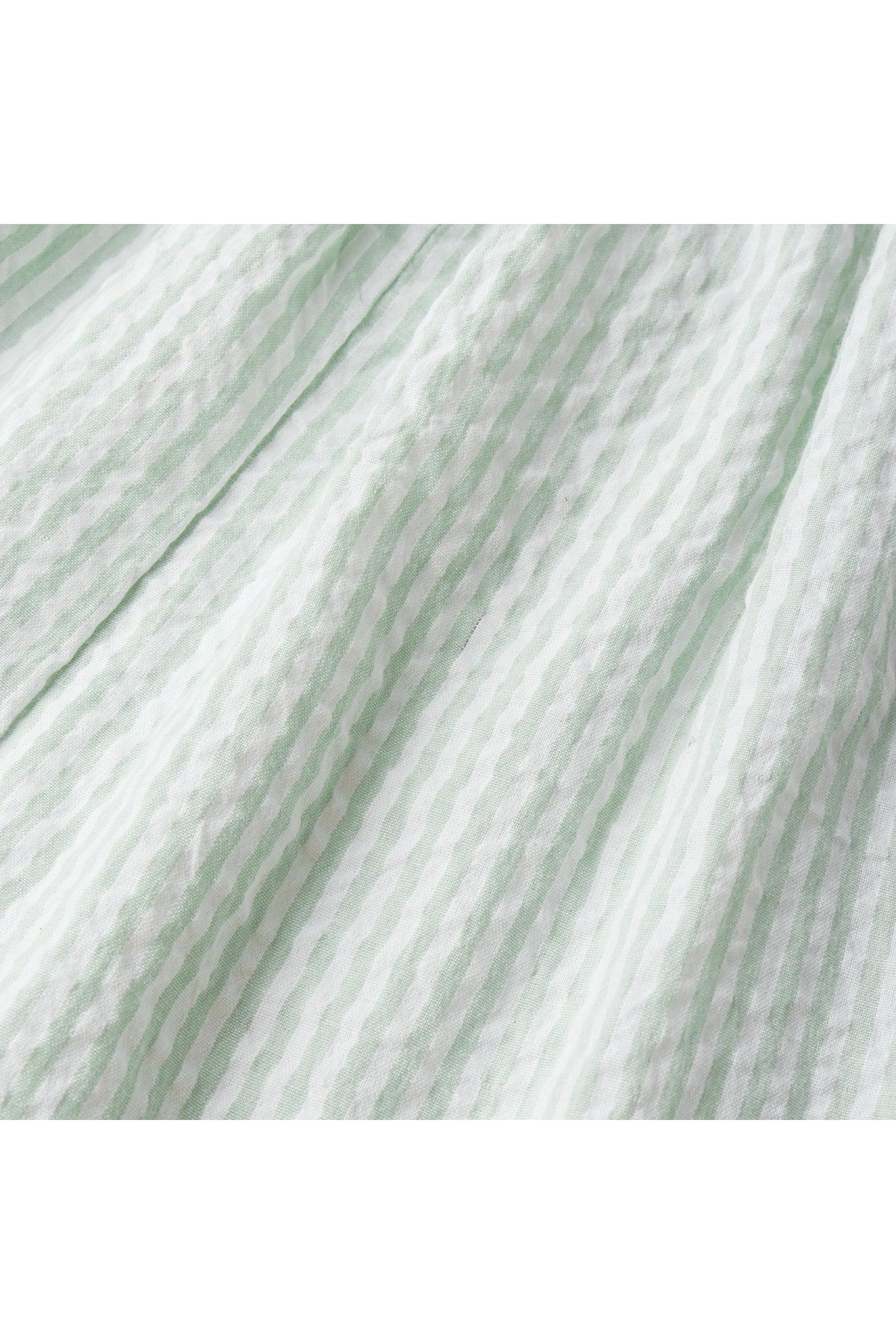 Close-up view of soft, organic cotton fabric featuring light basil green and white stripes, showcasing a textured, crinkled appearance ideal for a childrens flutter jumpsuit.