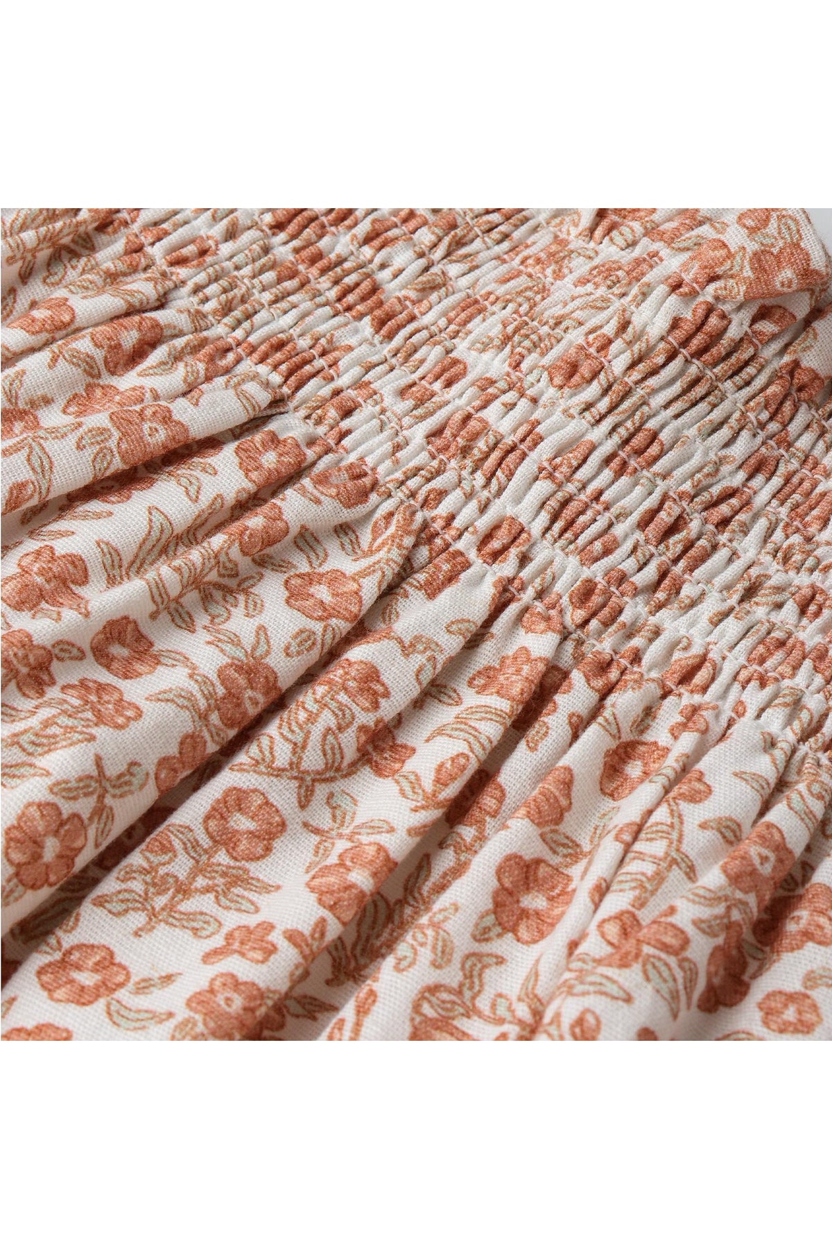 Close-up view of a floral patterned fabric featuring soft orange flowers on a cream background. The material appears lightweight and breathable, ideal for a comfortable summer outfit for children.