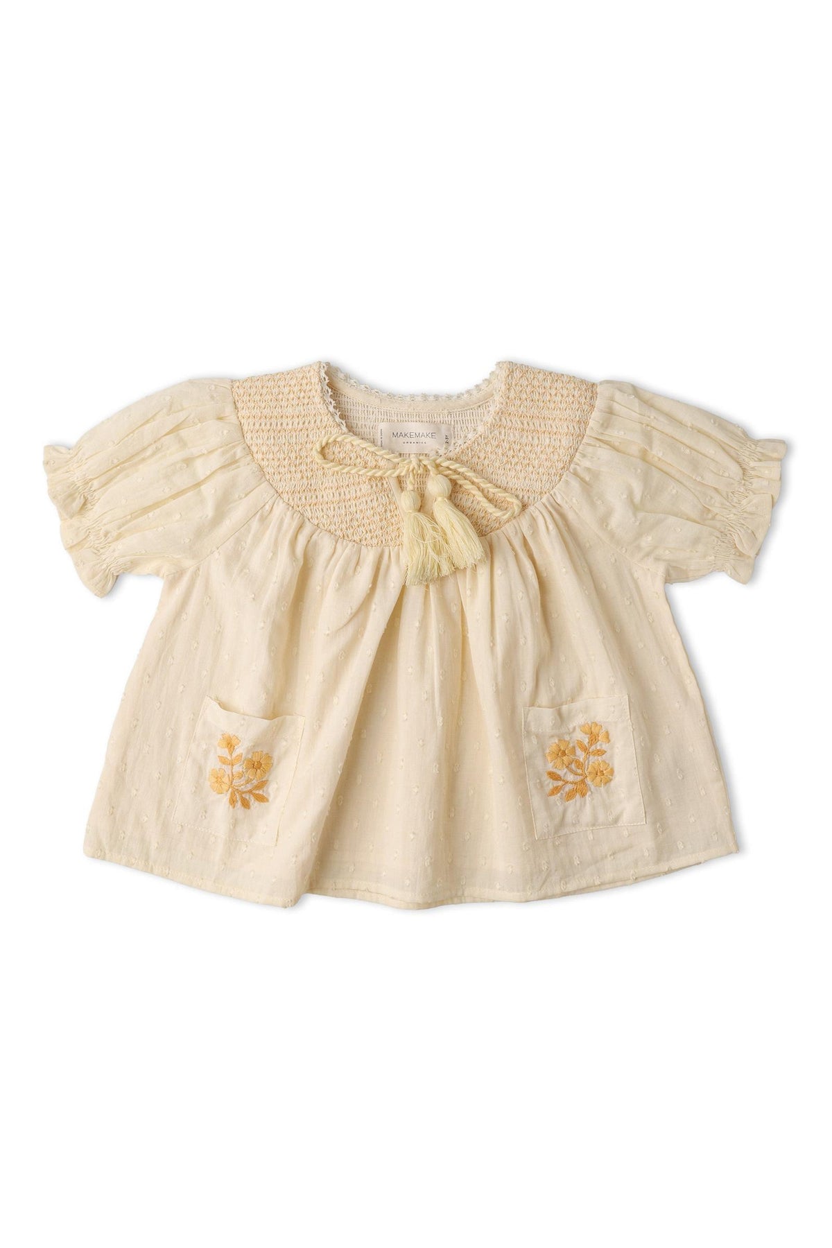 A soft, organic cotton smocked top in butter yellow features short puffed sleeves, a textured weave, and delicate embroidery on the pockets, perfect for sunny day outings.