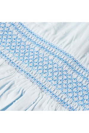 Close-up of light blue organic cotton fabric featuring delicate smocking details. The intricate blue stitching adds a vintage-inspired touch, perfect for childrens wear by Makemake Organics.