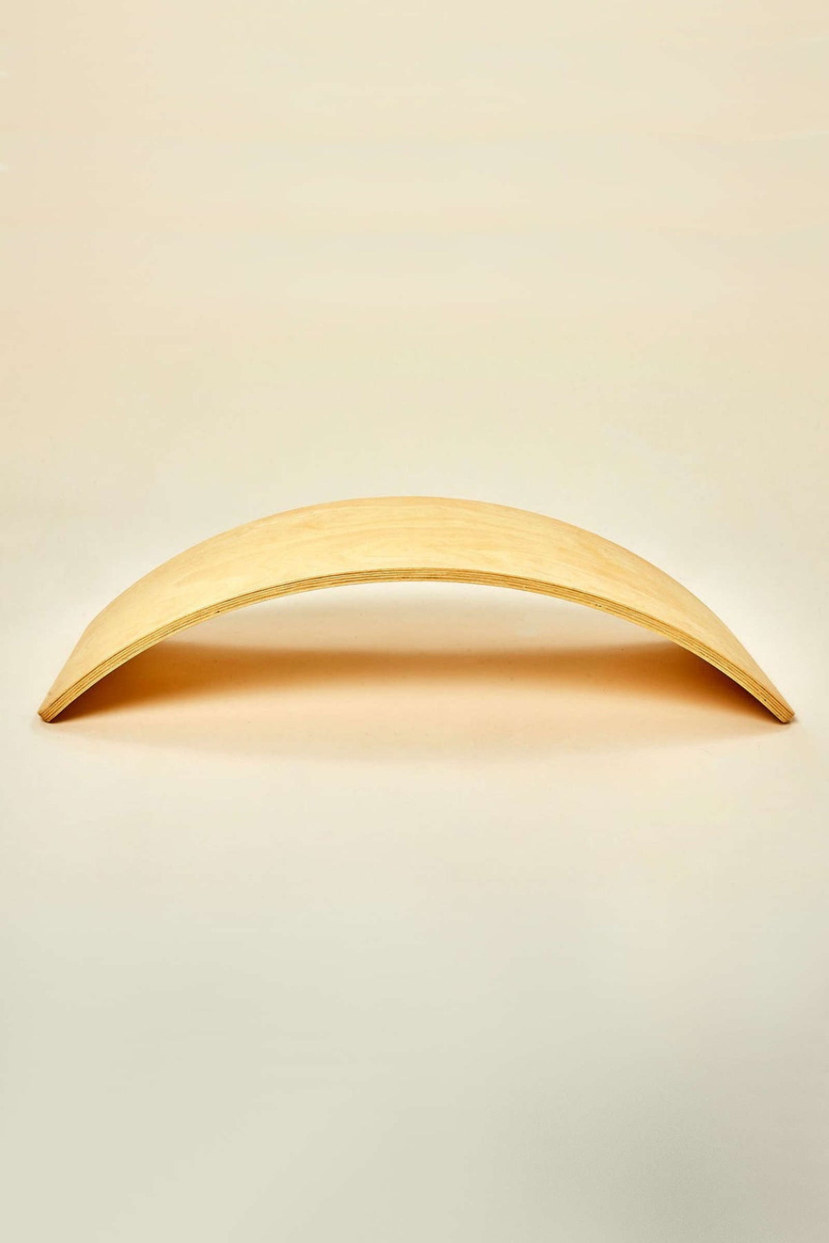 A natural wood balance board features a smooth, curved design, ideal for imaginative play and physical activity. Its sustainable construction promotes balance and coordination for children of various ages.