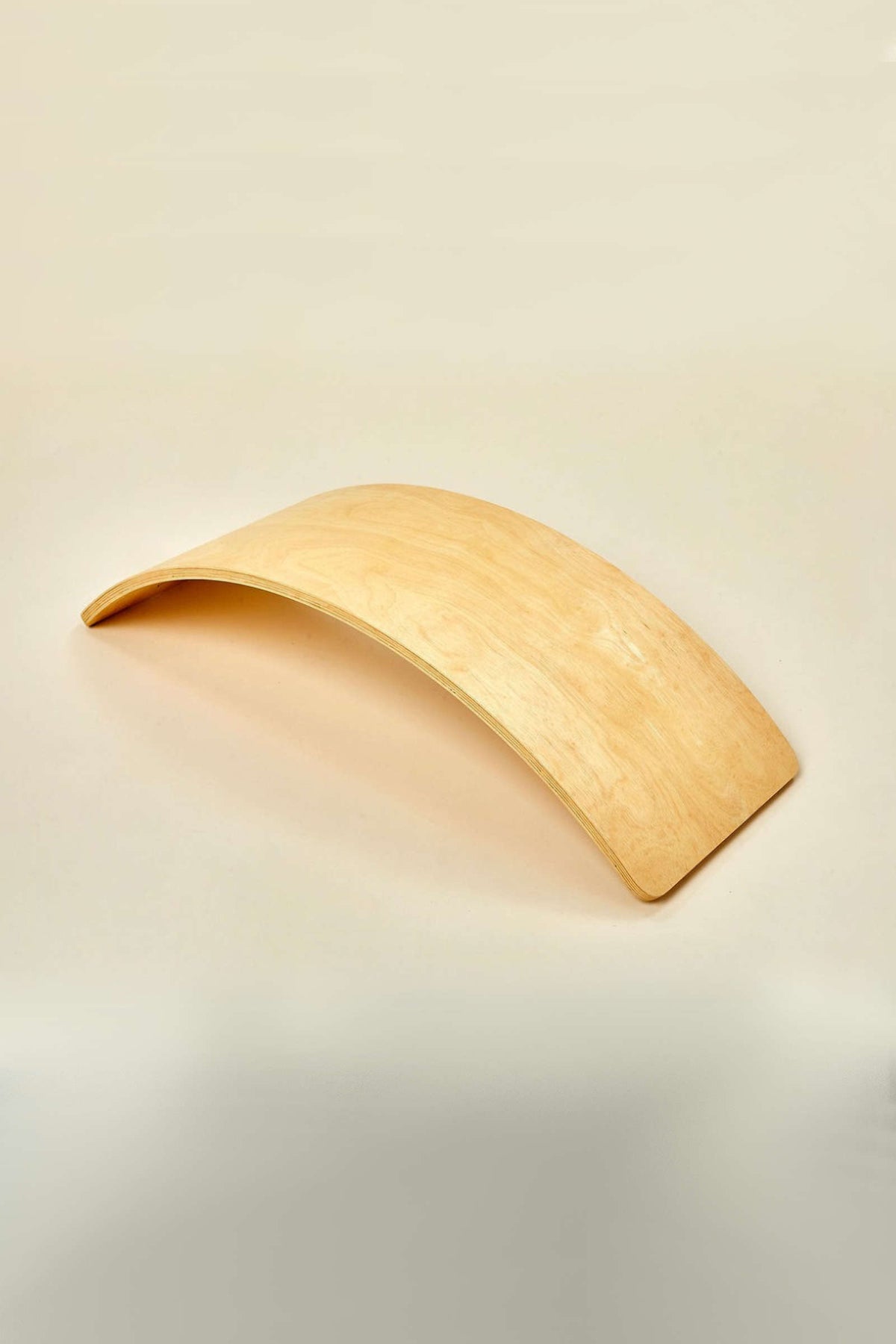 A smooth, curved wooden balance board rests on a neutral background. Its natural finish highlights the sustainable material, making it perfect for imaginative play and developing balance skills.