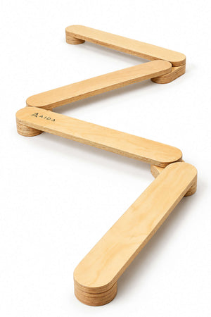 The image features a zigzag wooden balance beam from Aida, showcasing a natural finish and smooth edges, designed for childrens play and coordination development. Ideal for active, eco-conscious families.