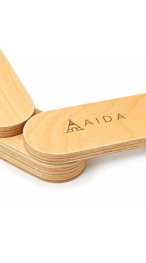 Close-up of smooth, natural wood balance beams featuring the engraved brand name AIDA. The beams are designed for childrens active play and are made from sustainable materials.