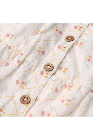 Close-up of a lightweight, floral-patterned fabric showcasing soft pastel flowers and a grid design, featuring wooden buttons that enhance the organic aesthetic of the dress. Ideal for spring wear.