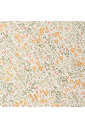 A close-up of a floral fabric featuring a light cream background adorned with delicate orange, pink, and green flowers. The soft, organic cotton material showcases a charming, nature-inspired pattern.