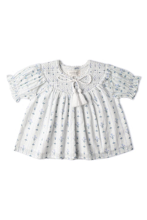Light blue organic cotton top featuring delicate floral patterns and a smocked neckline with a tassel tie. The short sleeves add a breezy touch, perfect for warm days.