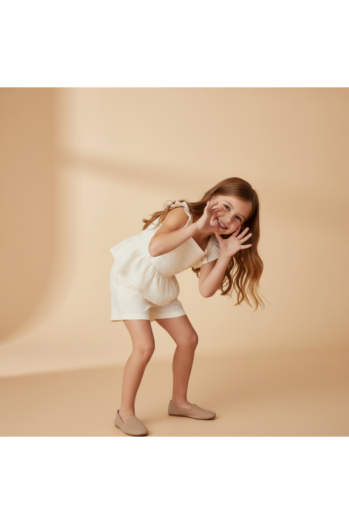 A girl playfully poses in a light ivory eyelet top and matching shorts set, showcasing delicate embroidery and a breezy silhouette, perfect for warm-weather outings.