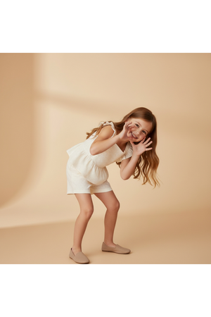 A girl playfully poses in a light ivory eyelet top and matching shorts set, showcasing delicate embroidery and a breezy silhouette, perfect for warm-weather outings.