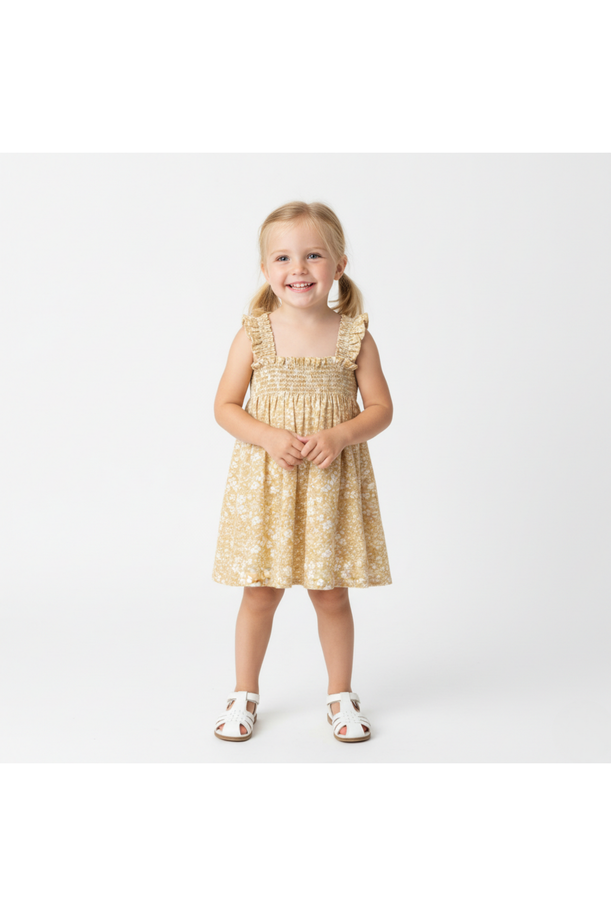 A smiling young girl stands in a yellow blossom smocked sundress, featuring ruffled straps and a flowy silhouette, perfect for warm summer days. The dress is made from breathable materials.