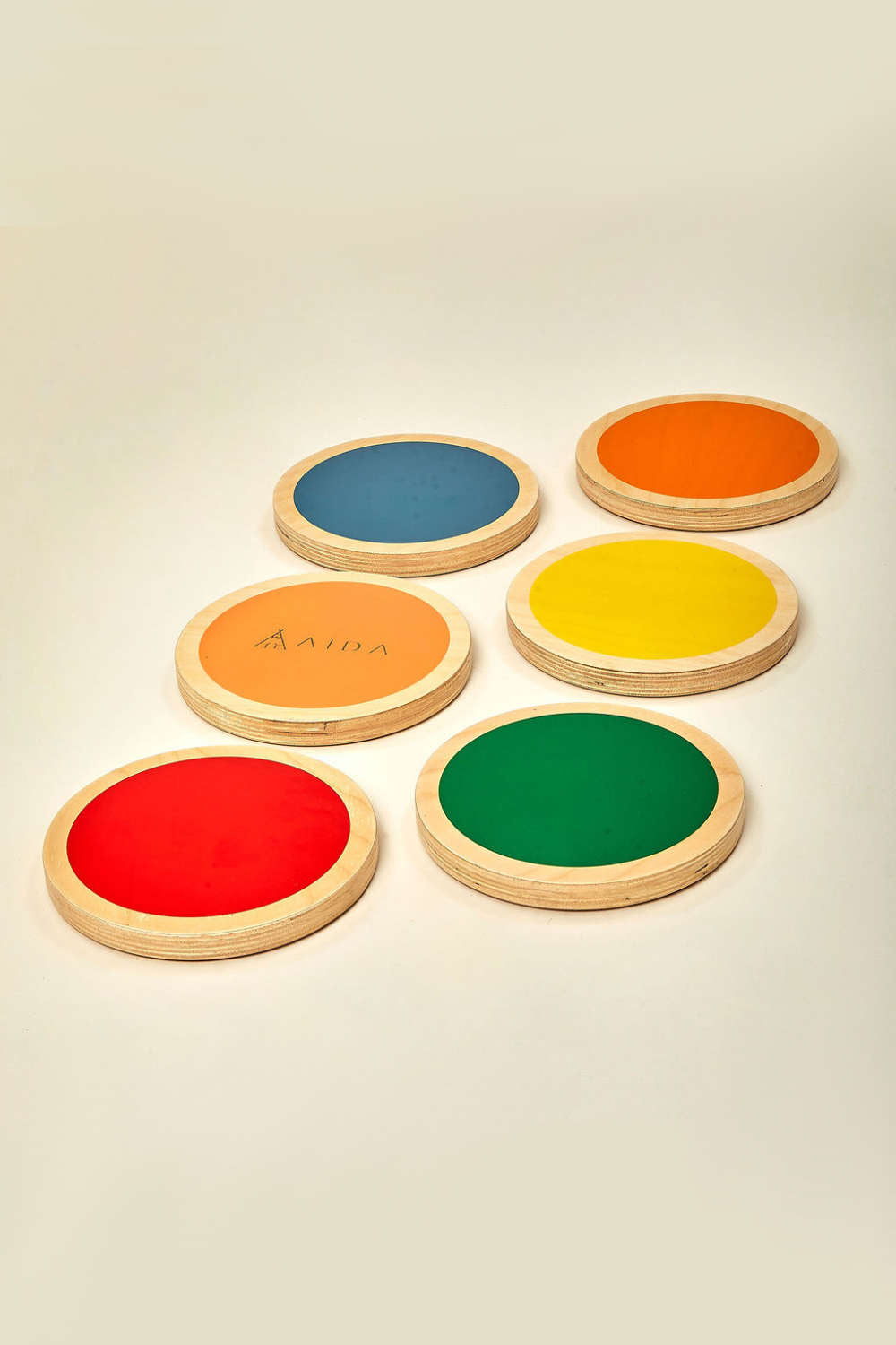 Six colorful, circular wooden stepping stones are arranged on a light background, featuring vibrant hues of red, orange, yellow, green, and blue, perfect for imaginative play and balance activities.