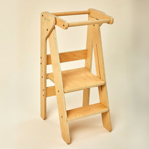 A wooden educational tower featuring a natural finish, designed for toddlers to safely reach counter height. Its sturdy construction promotes independence during cooking and other family activities.