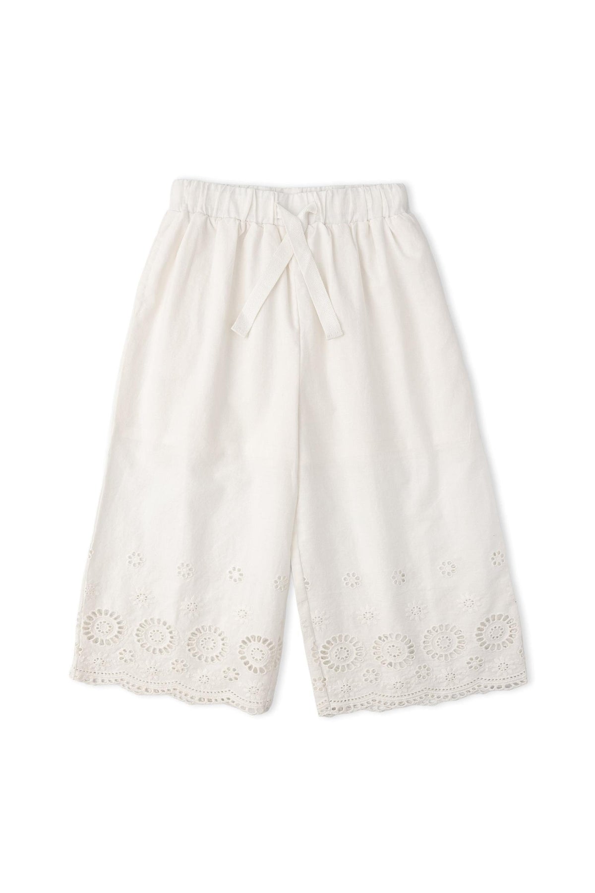 Light ivory culotte pants made from organic cotton, featuring intricate eyelet embroidery along the hem. These breezy, comfortable pants are perfect for warm-weather outings and celebrations.