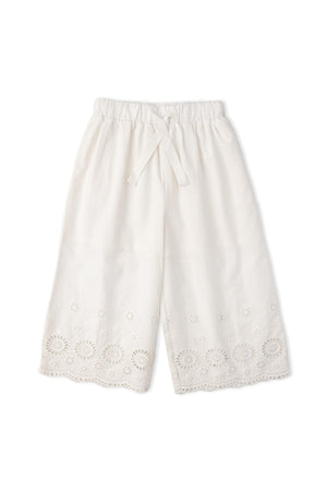 Light ivory culotte pants made from organic cotton, featuring intricate eyelet embroidery along the hem. These breezy, comfortable pants are perfect for warm-weather outings and celebrations.