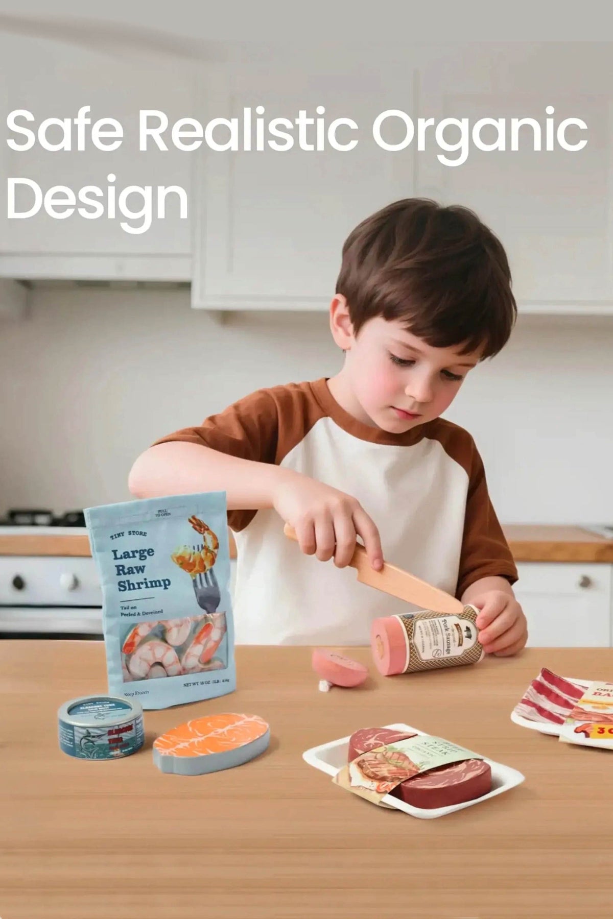 A young boy in a brown and white shirt uses a wooden playknife to cut a piece of toy meat, surrounded by realistic play food items in a bright kitchen.