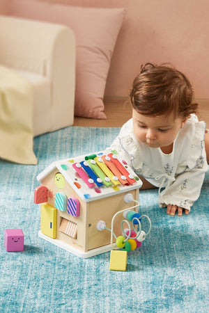 Baby playing with a colorful wooden toy on a blue carpet
