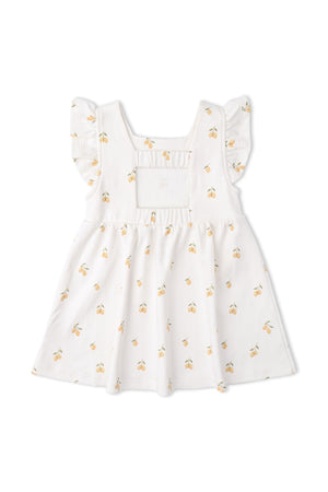 A white cotton dress featuring a cheerful lemon print, with ruffled sleeves and a cutout back. This organic dress is designed for comfort and style for young children.